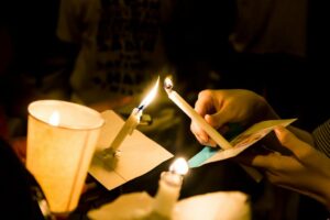 Group of people holding candle vigil in darkness seeking hope, worship, prayer